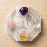 Clear octagonal selenite charging plate with engraved yin yang and four polished gemstones for crystal healing