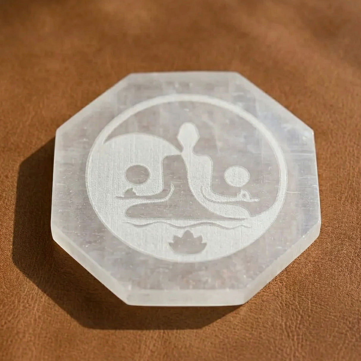 A translucent frosted selenite charging plate octagonal with etched meditating figures lotus flower design for healing stones