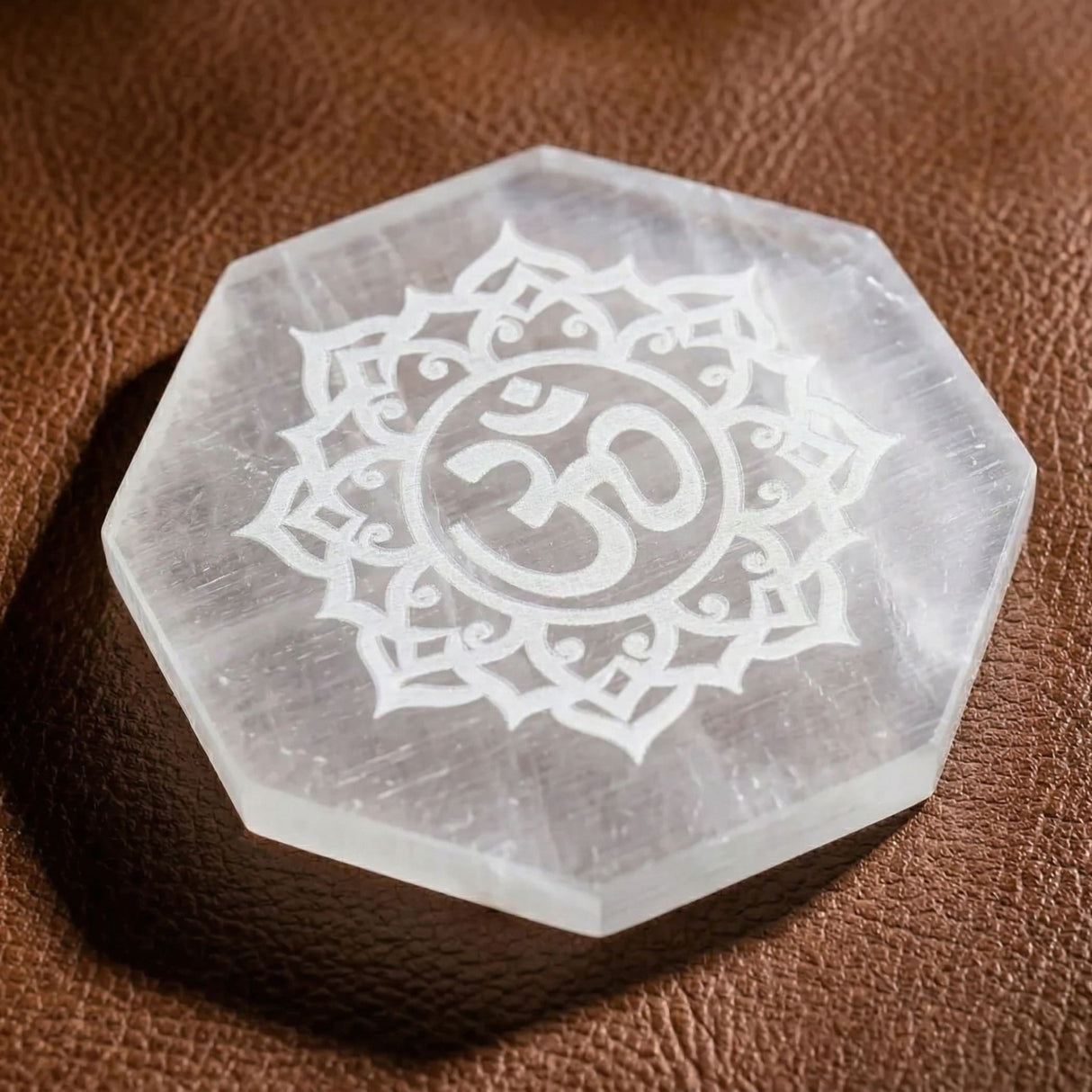 Clear hexagonal selenite charging plate with engraved om symbol and floral mandala for crystals and healing stones