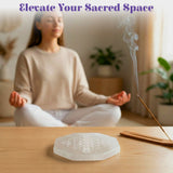 A translucent white selenite charging plate with etched geometric pattern for crystals and healing stones
