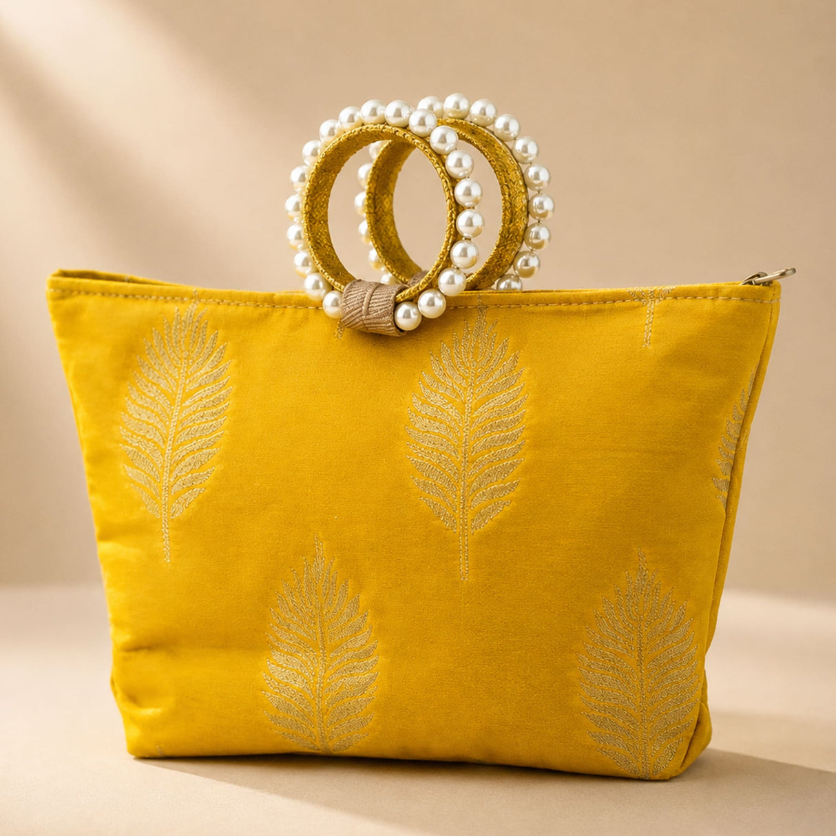 A vibrant yellow silk handbag with silver leaf embroidery and pearl-adorned woven handles for Eid and wedding favors