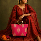 A vibrant pink silk handbag with gold leaf patterns and a pearl-encrusted handle for Eid and wedding favors