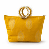 A vibrant mustard-yellow silk handbag with gold-embroidered leaf patterns and pearl-adorned handle for Eid and wedding favors