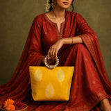 A vibrant yellow silk handbag with gold leaf embroidery and pearl-adorned handle for Eid and wedding favors