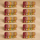 A set of colorful silk thread bangles with gold-tone kundan embellishments and dangling beads for indian weddings
