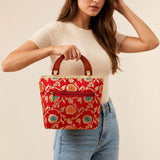 A vibrant red traditional Indian embroidered silk handbag with gold and teal floral designs and wooden handles for festive use