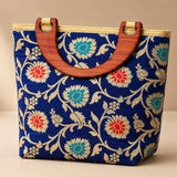 Traditional Indian embroidered silk blue handbag with red teal gold floral patterns and wooden handles for festivals and weddings