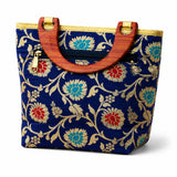 Blue traditional Indian embroidered silk handbag with intricate gold turquoise red floral pattern and wooden handles for festivals