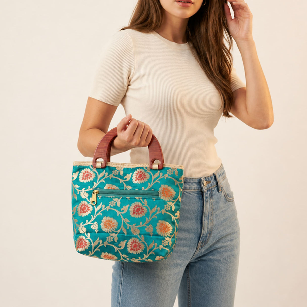 Teal floral-patterned traditional Indian embroidered silk handbag with brown leather handles and gold-tone hardware for festivals