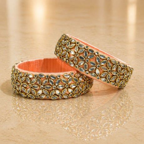 Ornate peach-colored Indian silk thread bangles with gold-toned settings and sparkling marquise-cut stones for women