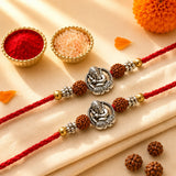 Designer silver tone ganesha rakhi with red cotton thread and brown rudraksha beads for raksha bandhan protection