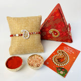 Red beaded designer pure silver om rakhi with diamond accents displayed on textured burlap cushion for Raksha Bandhan