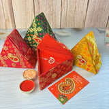 Red triangular brocade box with gold floral pattern and paisley clasp for designer pure silver om rakhi gift set