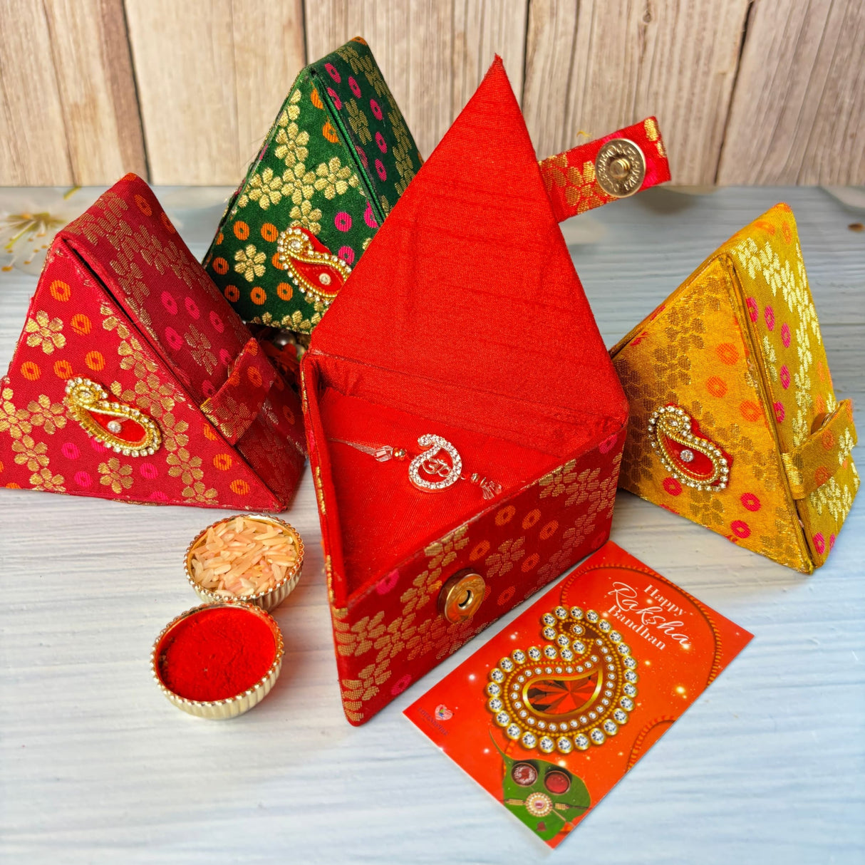 Vibrant red brocade fabric box with gold paisley embroidery and golden clasp for designer pure silver Om rakhi