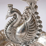 Silver plated peacock diya oil lamp with intricate feather detailing and polished metallic finish for home pooja mandir