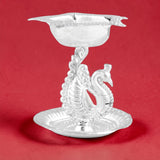 Silver plated peacock diya oil lamp with intricate detailing and scalloped rim for home pooja mandir and Diwali decor