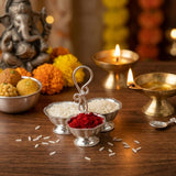 Silver plated three-compartment offering tray with ornate handle holding white rice and red powder for puja and festivals