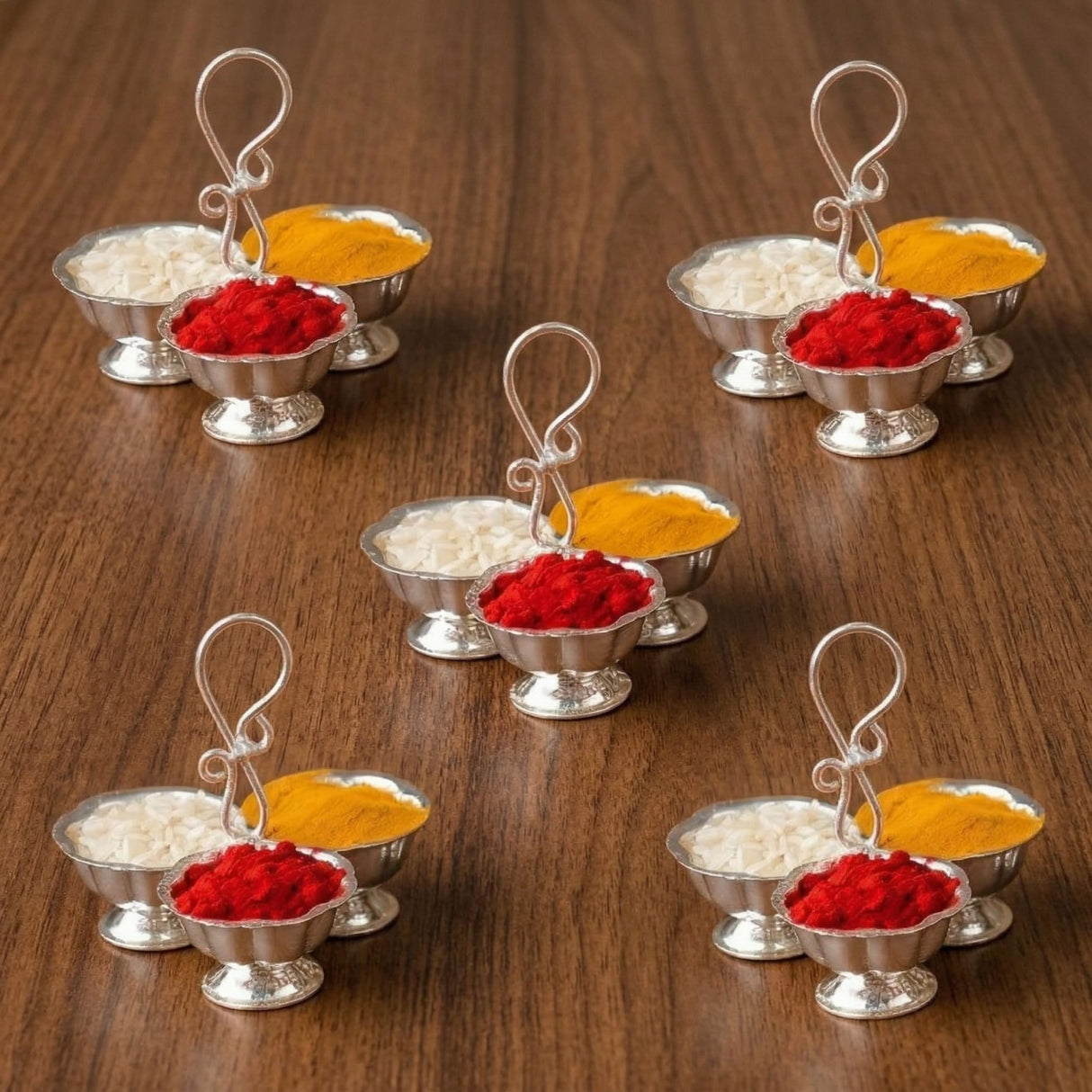Silver plated haldi kumkum holder with ornate curved handles containing red powder and yellow turmeric for puja rituals
