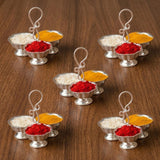Silver plated haldi kumkum holder with ornate curved handles containing red powder and yellow turmeric for puja rituals