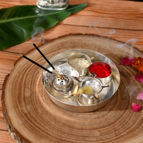 Silver plated incense burner with intricate floral detailing holding two burning sticks and decorative diya for pooja rituals