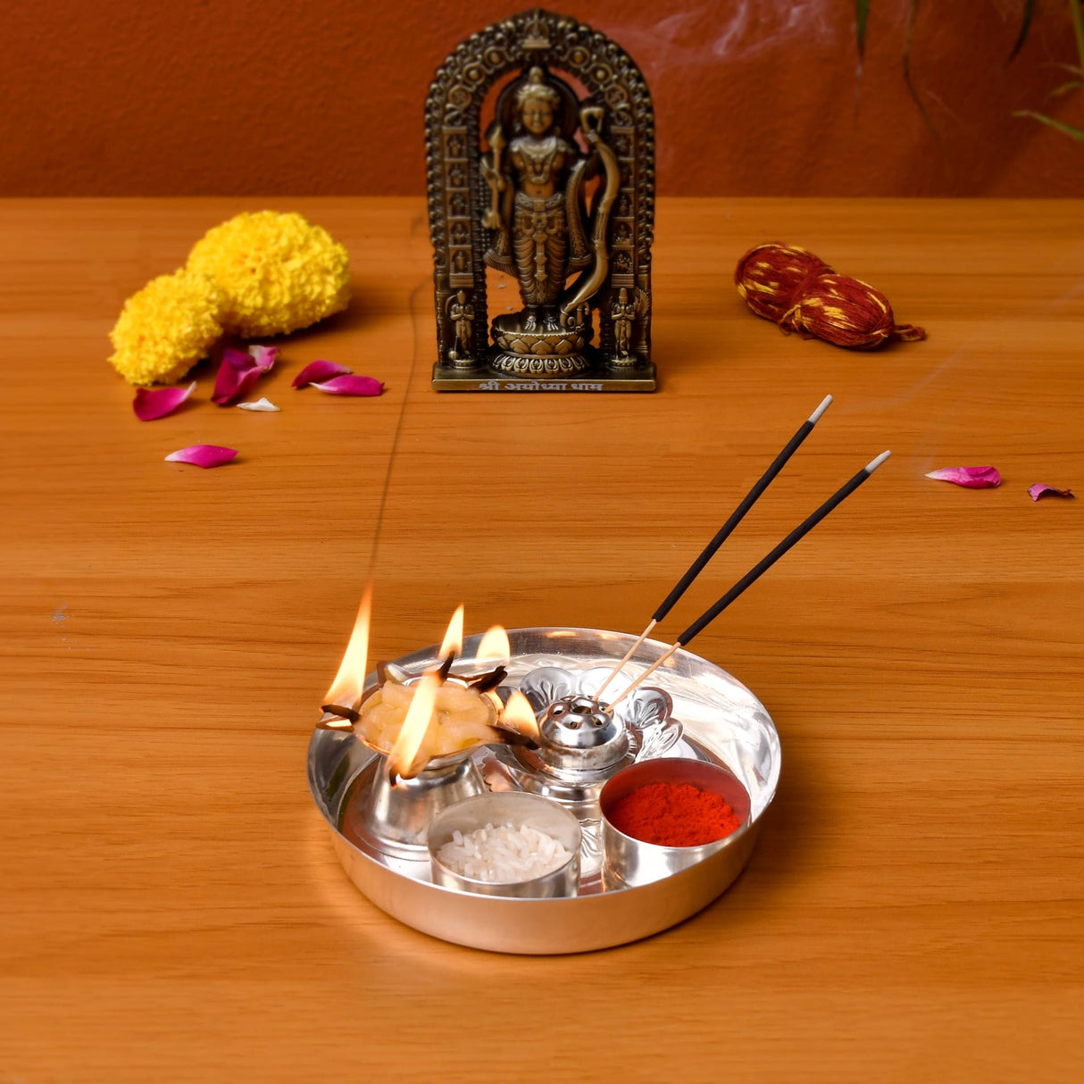 Silver plated pooja thali set with three compartments holding incense sticks burning oil lamps and red powder for rituals