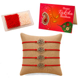 Four red cord rakhi bracelets with gold-toned rose metal pendants on beige burlap for brother and bhabhi gift