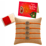 Set of four orange cord rose charm rakhi with silver metal floral charms on a burlap cushion for brother and bhabhi