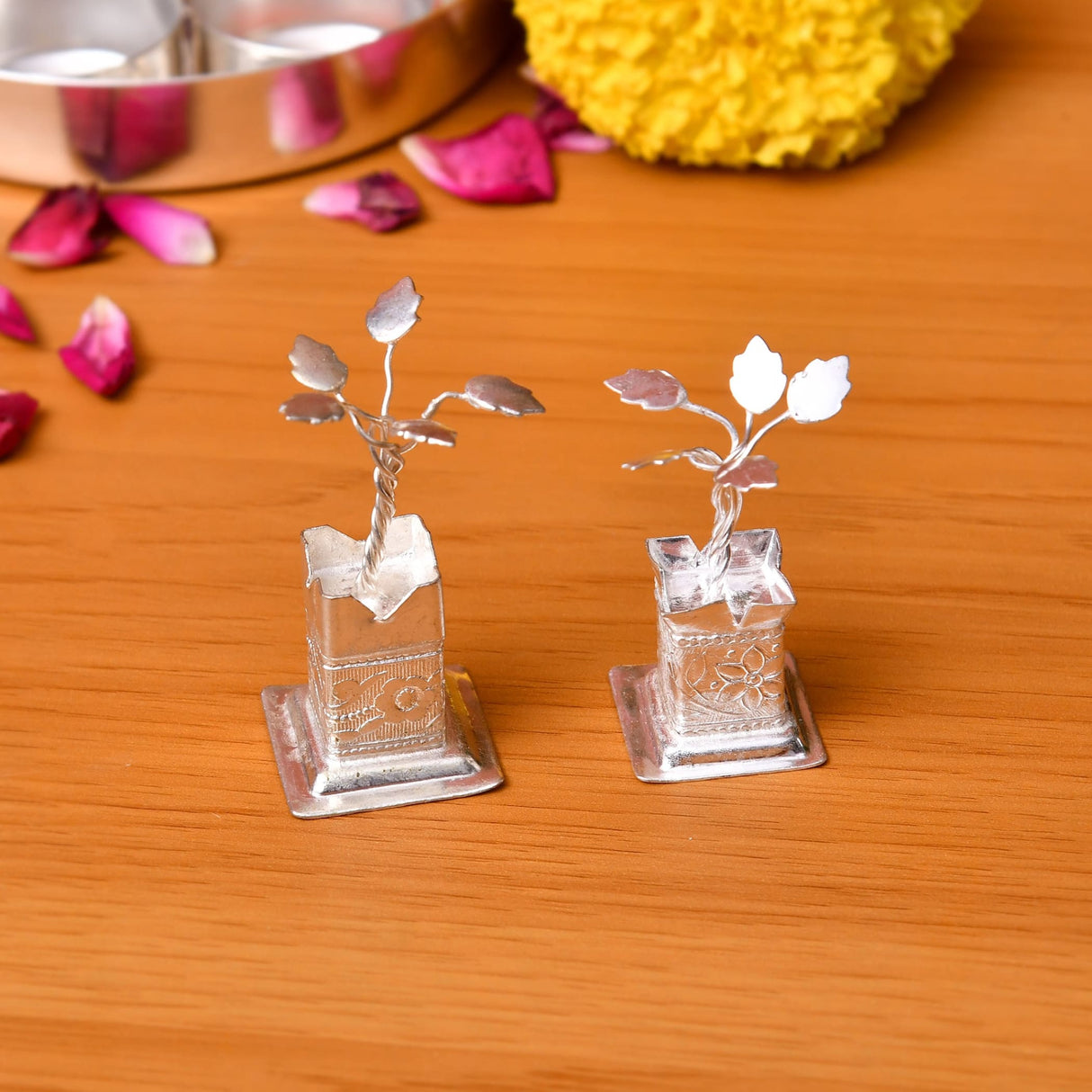Two silver plated tulsi plant figurines with detailed leaves on engraved square bases for home pooja mandir decor