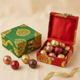 Red and gold ornate handmade brocade jewelry box with velvet interior filled with assorted chocolates for wedding favors