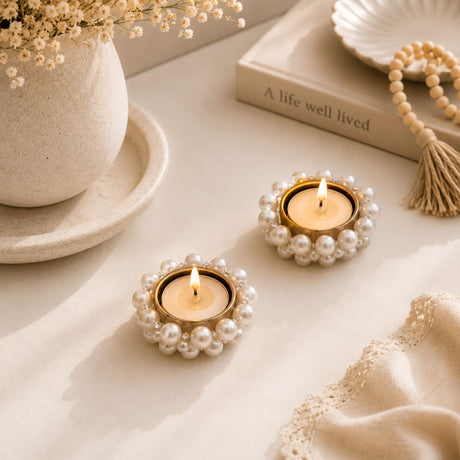 Two elegant gold-rimmed small pearl tealight candle holders with white pearls and flickering candles for festive décor