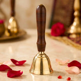 Polished solid brass hand call bell with dark brown wooden handle and horizontal grooves for grip used in prayer and ceremonies