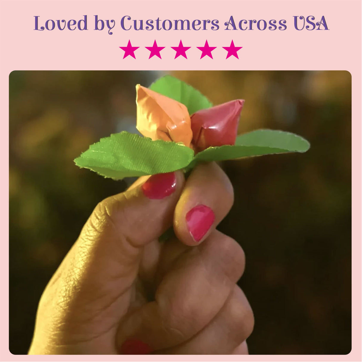 A delicate handcrafted flower made from glossy orange and pink candy wrappers with textured green leaves for haldi kumkum packets bulk strawberry style mini packs premium sindoor and turmeric powder combo