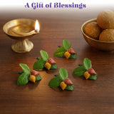 Green and yellow miniature leaf-shaped haldi kumkum packets with red accents on wooden surface for indian wedding puja