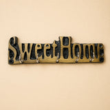 Brass-colored handmade wooden sweet home wall-mounted key holder with black cast metal lettering and five silver hooks