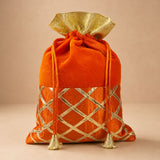 Orangish-red velvet potli bag with gold metallic lattice embroidery and tassels for Indian festive and wedding use