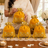 Traditional indian velvet potli bags in golden with silver lattice embroidery and gold tassels for festive occasions