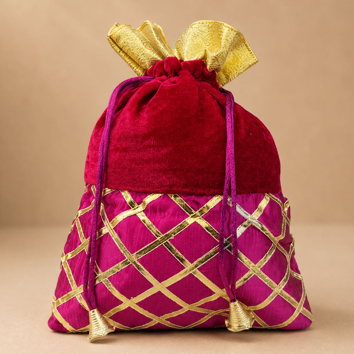 Traditional Indian velvet potli bag in red and magenta with gold gota patti lattice work and golden bow for festive use