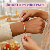 A vibrant orange and gold traditional floral pearl bhai bhabhi rakhi bracelet with white pearls and colorful beads
