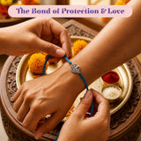 A delicate blue cord tree of life charm rakhi with silver-toned circular charm for brother and bhabhi protection gift