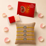 Four yellow corded tree of life charm rakhis with silver pendants on a beige burlap cushion for Raksha Bandhan gift