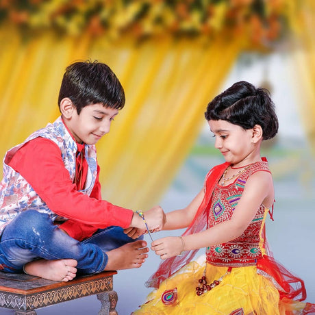 Two children in colorful traditional Indian attire tying a rakhi bracelet.