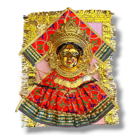 Golden Hindu deity figure with ornate red and green fabric for Varalaxmi Vratam puja