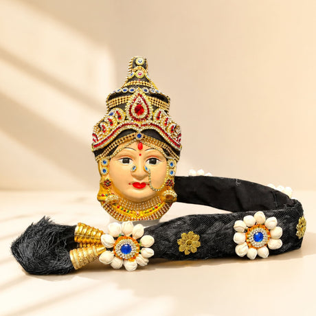 Vara Lakshmi goddess face set with black headpiece, gold embellishments, white flowers, blue gemstones for Navaratri pooja