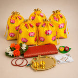 Bright yellow satin drawstring potli bags with pink lotus prints and gold-tipped cords for navaratri and puja gifts