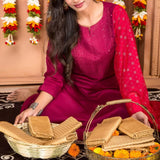 A woman wearing a vibrant magenta traditional outfit with white floral embroidery in varalakshmi vratham gift hamper for women