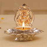 Silver and gold-plated metal diya with intricate deity design in varalakshmi vratham gift hamper for hindu pooja rituals