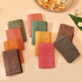 A collection of vibrant fabric squares in red green gold and purple featured in varalakshmi vratham gift hamper kit
