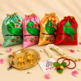 Four satin drawstring potli bags in mint green pink gold and red with green parrot print for varalakshmi vratham gift hamper