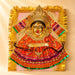 A vibrant varalaxmi goddess face set with golden deity portrait, embroidered dress, and jewelry for Navaratri pooja
