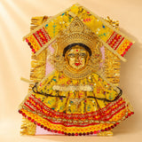 Golden ornate varalaxmi goddess face idol adorned with vibrant yellow and red embroidery dress for navaratri pooja